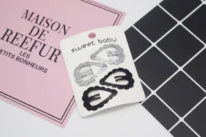 Gros plan de barrettes à paillettes en forme de cœur, noir et argent, sur carton