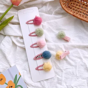 Set of 5 colorful plush ball hair clips for girls in pastel colors on white fabric