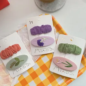 Detail van handgemaakte geborduurde bloemen haarclips met geplooide textuur in pastelkleuren