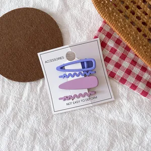 Lot de quatre barrettes en métal violet mat aux motifs évidés sur carte de présentation
