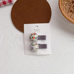 Detalle de dos pinzas para el cabello con estampado floral para niña en tarjeta blanca