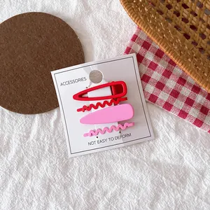 Détail macro de barrettes à cheveux en métal mat rouge et rose pour enfants sur carte