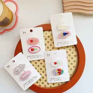 Primer plano de clips para el pelo de acrílico con animales y flores sobre cartón