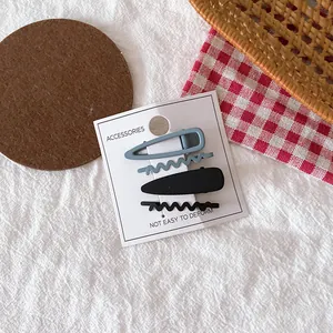 Lot de quatre barrettes à cheveux mates bleu brume et noir sur carte d'affichage
