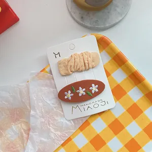 Haarspeldjes set met geborduurde bloemen en oranje geplooide stof op dienblad