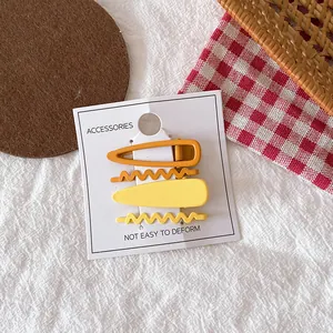 Détail de quatre barrettes en métal dégradé jaune et orange sur carte de présentation