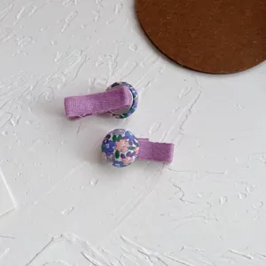 Detalle de horquillas con botones florales de tela y cinta de grosgrain púrpura