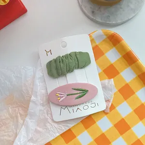 Detail van geborduurde tulp en groene ruches op twee haarclips voor meisjes