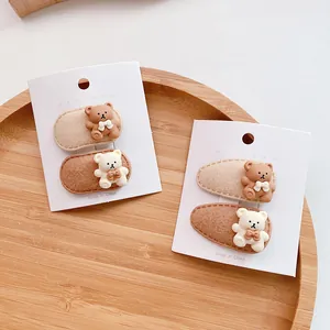 Detail of cute bear hair clips for girls on a wooden tray with soft beige and brown colors