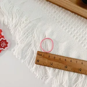 Pack of 30 pink high-elasticity hair ties for kids on white tassel tablecloth