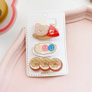 Detalle de tres lindas pinzas de acrílico con osito y donas en tarjeta de exhibición