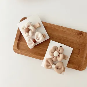 Detail of fabric bow and floral hair clips for kids in warm beige and tea tones