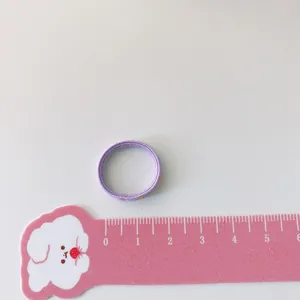Violetter elastischer Kinderhaargummi mit 3 cm Durchmesser auf einem rosa Lineal
