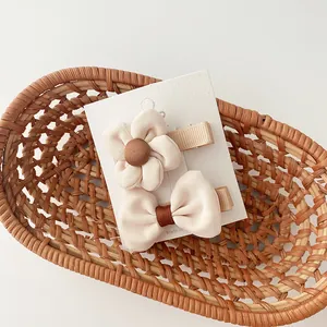 Detail of fabric bow and flower hair clips in milk tea colors on a display card