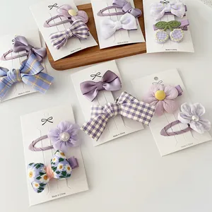 Detalle de pinzas de pelo en tela violeta con lazos y motivos de cerezas