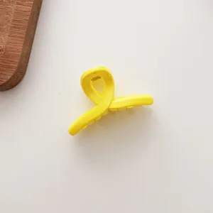 Détail de la mini pince à cheveux jaune brillant avec un design classique à emboîtement