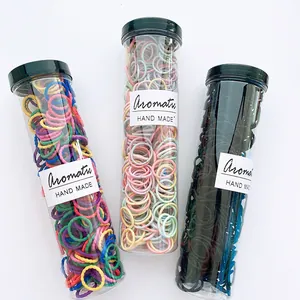 Close-up of three cylindrical containers filled with colorful elastic hair ties in candy tones