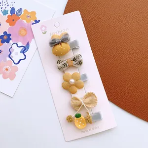 Detailed set of four yellow fabric bow and flower hair clips for girls on display card