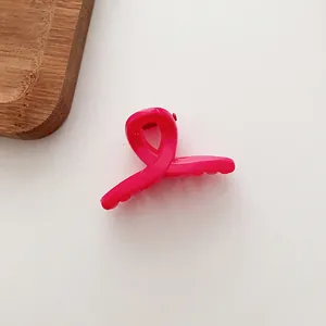 Détail d'une petite pince à cheveux rose fuchsia avec un design à boucles croisées