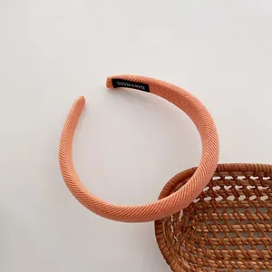 Detailansicht eines rosa Strickstirnbands mit handgefertigtem Etikett auf weißem Grund