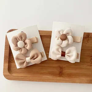Close-up of fabric flower and bow hair clips in milk tea tones on wooden tray