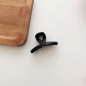 Détail d'une petite pince à cheveux noire en acrylique brillant sur un plateau en bois