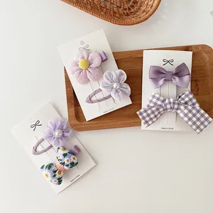 Detalle de pinzas para el cabello con lazos morados y flores en bandeja de madera