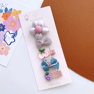 Set of 5 colorful kids' bow hair clips with flower and cherry patterns on display