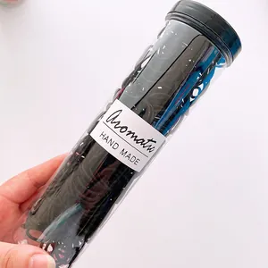 Detail of high-elasticity black hair ties in a clear cylindrical tube for kids