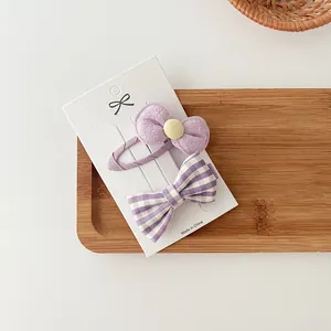 Detalle del set de 2 horquillas de lazo morado con botón amarillo y estampado de cuadros