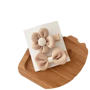 Apricot fabric flower and bow hair clip set for girls on a wooden tray display