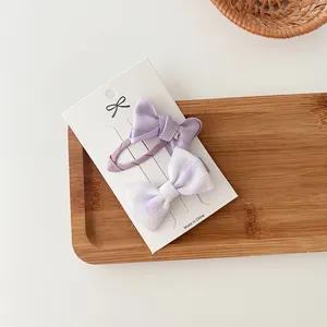 Detalle de dulces pinzas para el cabello con lazo púrpura en tarjeta con texturas