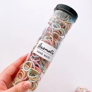 Macro view of macaron colored high elastic hair ties in a clear cylindrical storage tube