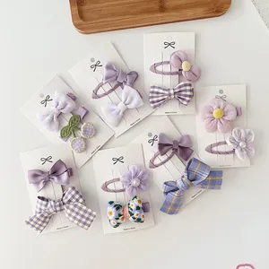 Detalle de lazos morados y clips de flores sobre un embalaje de cartón blanco