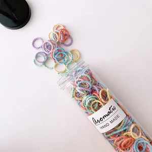 Macro view of macaron colored spiral hair ties spilling from a clear cylinder container