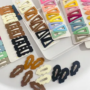 Detail view of colorful matte hair clips in various geometric shapes on a white card