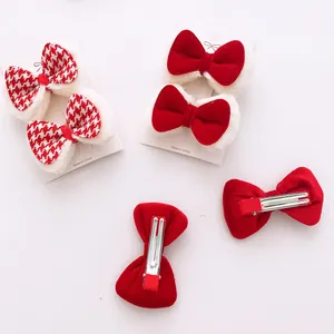 Detail view of red velvet and houndstooth bow hair clips with white faux fur trim on card