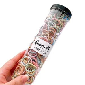 Jar of colorful braided elastic hair ties for kids in various soft candy colors