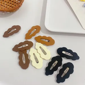 Detailed close-up of matte cloud-shaped hair clips in various warm earth tones