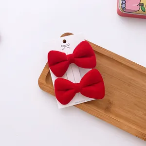 Close-up of two red velvet bow hair clips for girls on a white display card