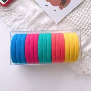 Colorful thick fabric hair ties set in a clear plastic box on white tassel background