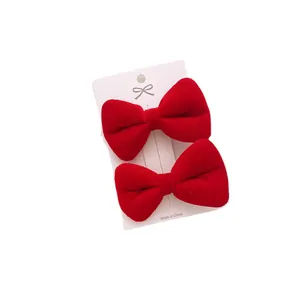 Pair of red velvet bow hair clips for girls on a white card display for autumn and winter