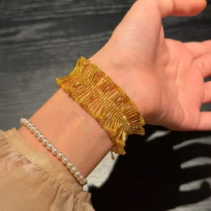 Close-up shot of a vintage gold pleated ruffle lace bracelet paired with a pearl bracelet