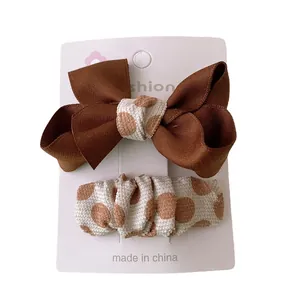 Bruine satijnen strik en beige polkadot haarclips op displaykaart voor meisjes