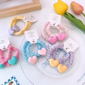 Gros plan de chouchous colorés avec pendentif cœur aux tons pastels doux sur cartes