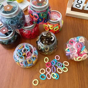 Macro shot of 100 colorful elastic hair ties in clear jars on a wooden table
