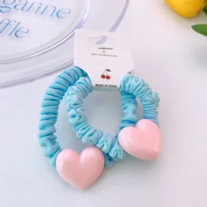 Détail de deux chouchous à volants bleu ciel avec des breloques en forme de cœur rose
