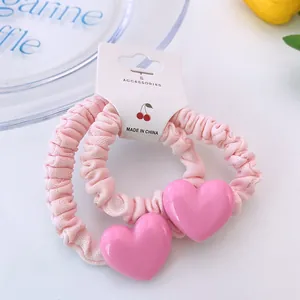 Détail de deux chouchous roses à volants avec pendentifs en cœur sur une carte