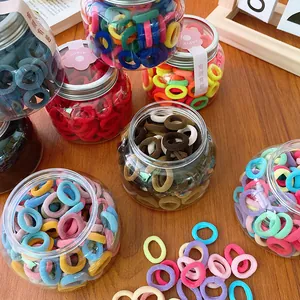 100pcs candy colored mini hair bands in transparent jar on a warm wooden background