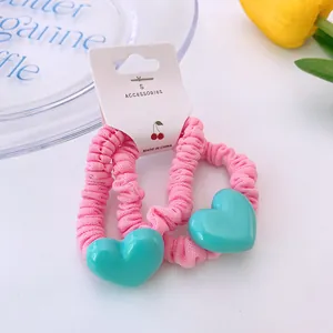 Détail de chouchous roses à volants avec breloques cœur vert menthe sur carte blanche